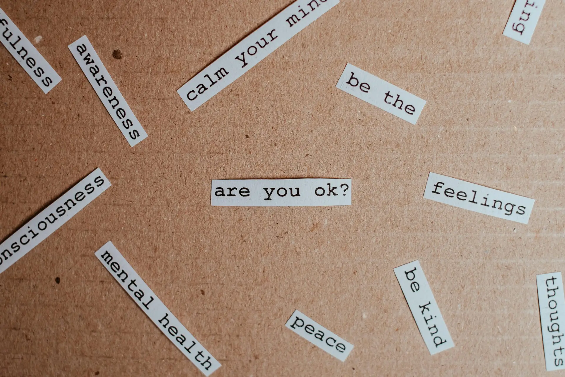 Cut-out words promoting mental health awareness on cardboard background.